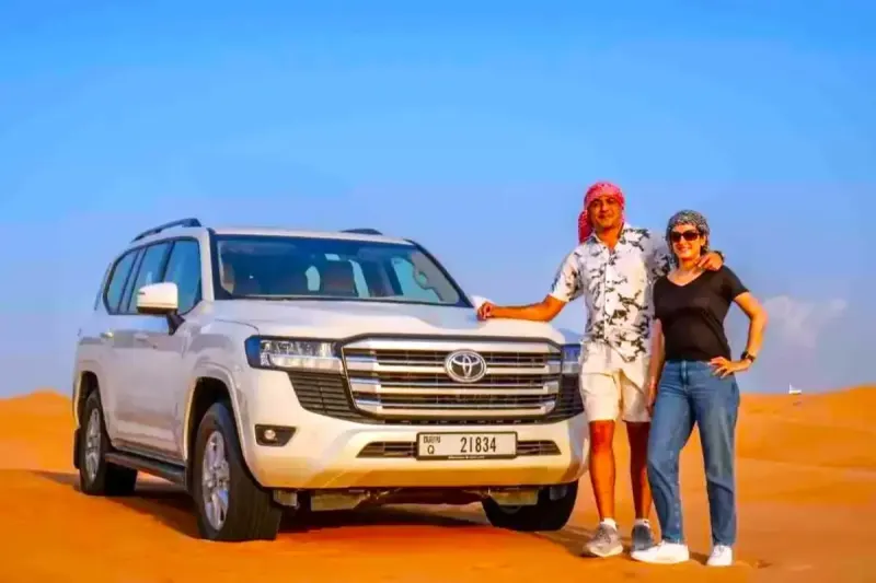 Couple standing beside their private Land Cruiser on a private desert safari in Dubai
