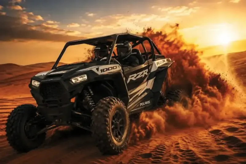 Polaris RZR 1000cc 2 seater dune buggy driving through the Dubai red dunes at sunset